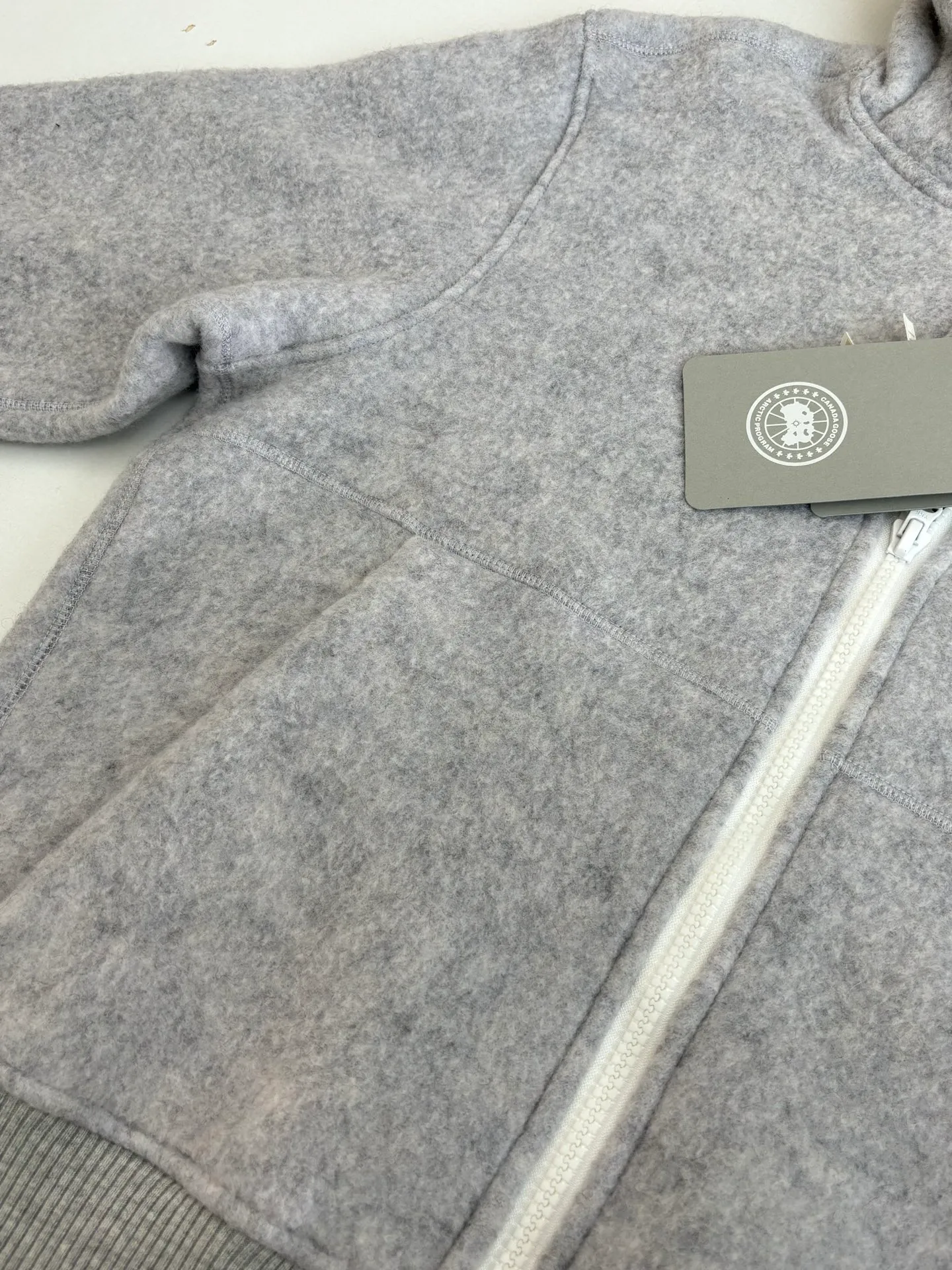 P810 Canada Goos*/Big Goose Fleece Badge Hooded Jacket The fabric is made of wool as the main body, with a very small amount of spandex and polyester fiber blended into the wool fleece fabric. The sleeves and hem are closed with 2×2 ribbing. Its strong elasticity can closely fit wrists and waists of different thicknesses, forming an effective 'seal' to prevent cold wind from blowing back. It can still maintain its original shape after repeated stretching and use, and is not easy to loose and deform. And the ribbed cuffs can convey a sense of design and enhance the visual beauty.  Size：S/M/L/XL